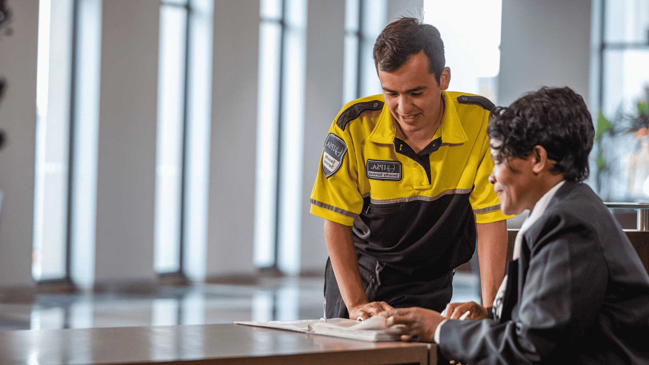Two security guards at desk reviewing training manual.
